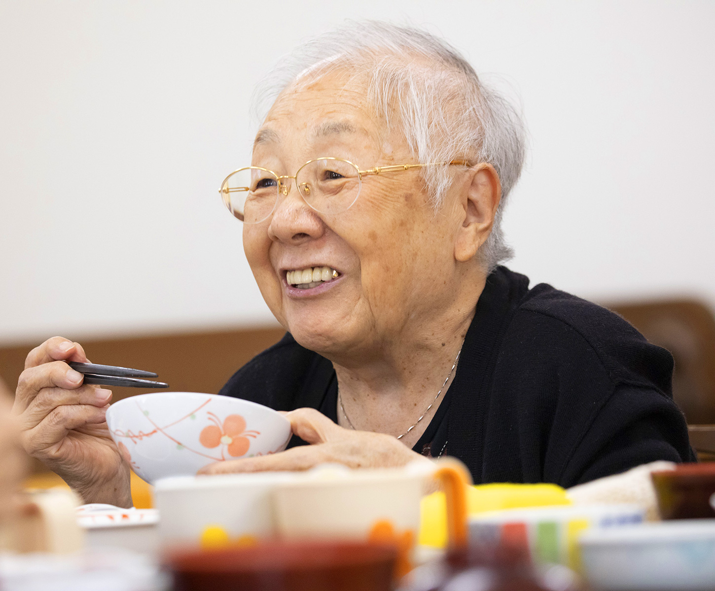 高齢者が食事中に笑顔を見せる、日常生活風景